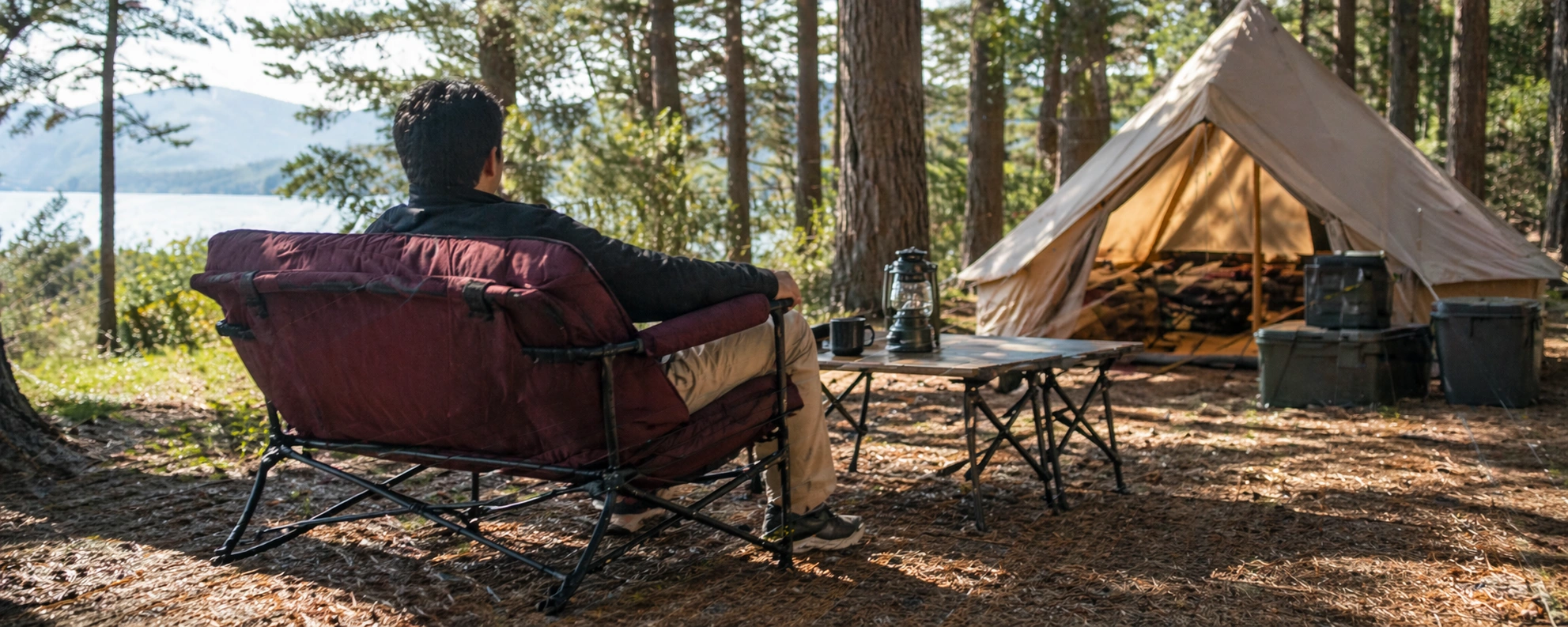 Person relaxing on a camping sofa at a campsite with tent in background