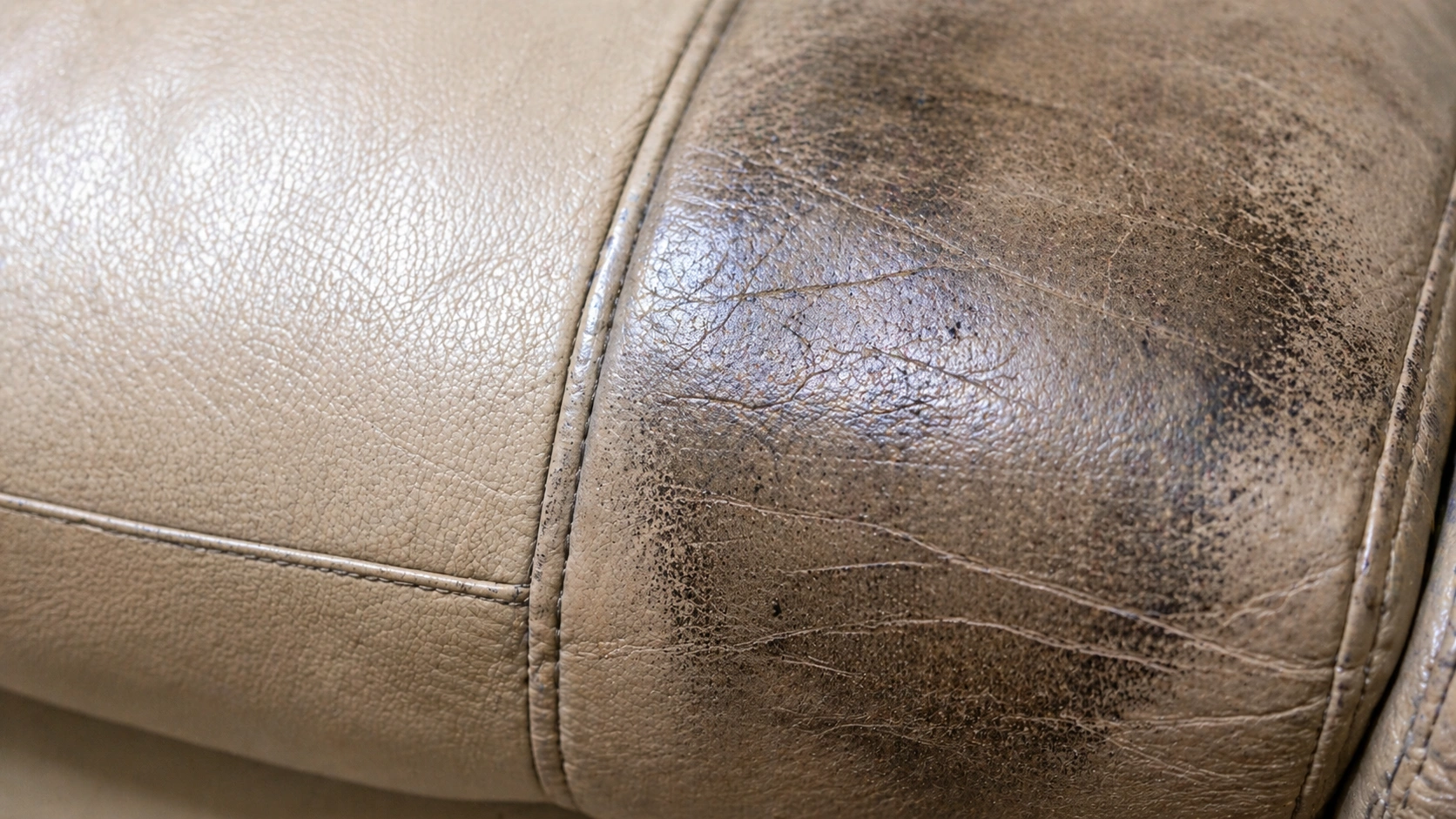 Close-up of dirt buildup on neglected leather sofa surface showing cracks and dullness
